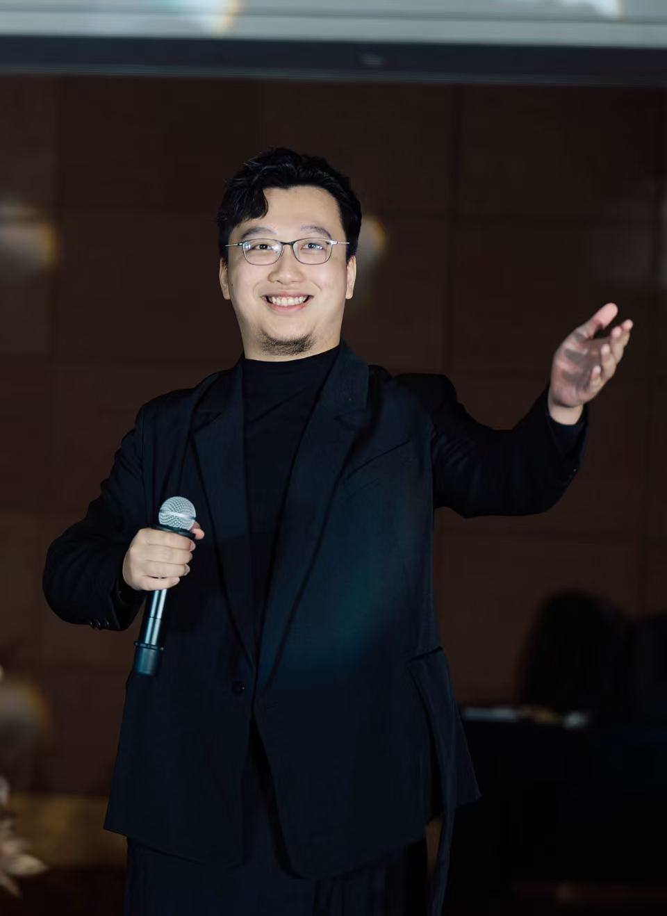 杨思捷在活动现场手持麦克风进行分享